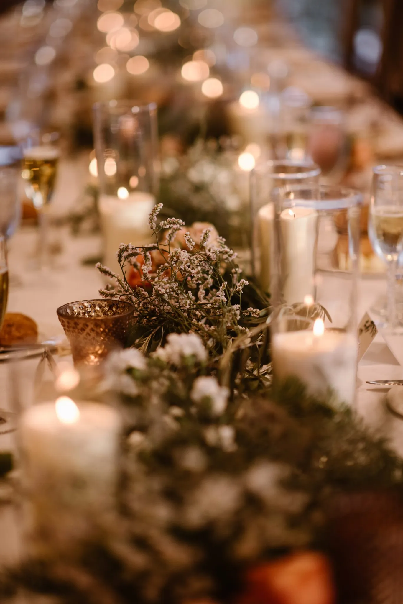 a long table set with candles, glasses, and a plant