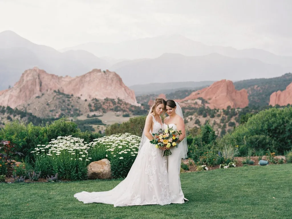 Bride and groom overlooking red rocks and Pikes Peak at a destination wedding venue in Colorado Springs.